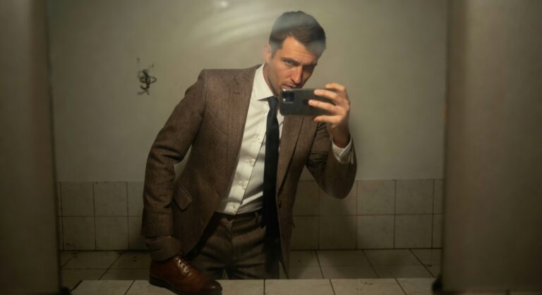 Man kneeling in tiled bathroom taking selfie in brown herringbone tweed suit jacket over white dress shirt and navy tie, with matching trousers and brown dress shoes