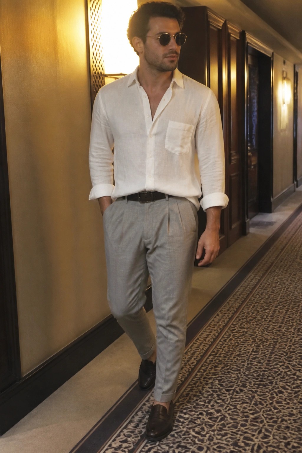 Stylish man in white linen shirt and gray trousers in elegant hallway