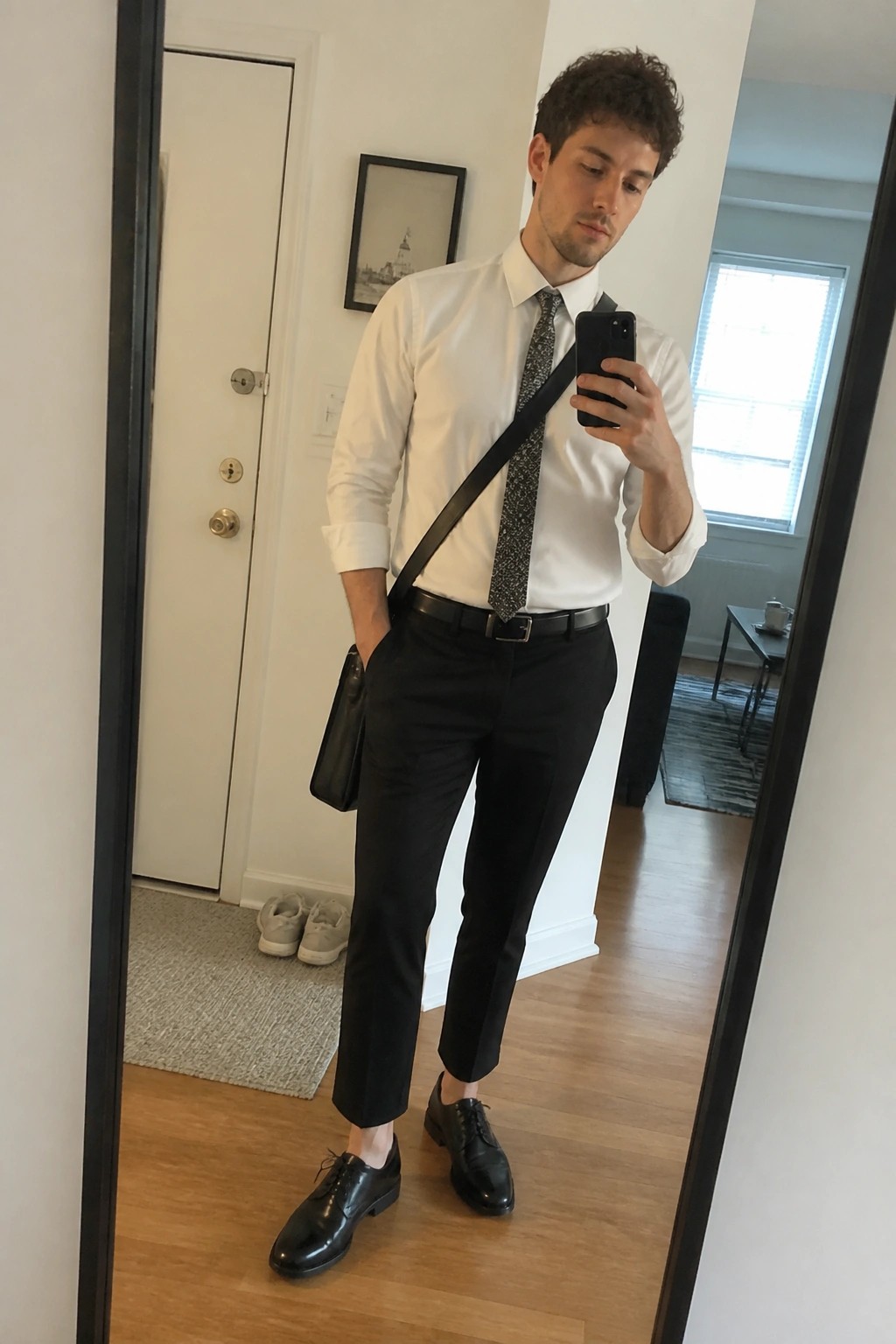 Man in white shirt and patterned tie taking mirror selfie with phone