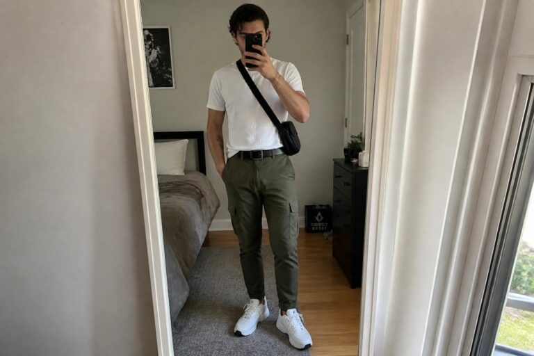 Man in white t-shirt and olive cargo pants taking a mirror selfie.