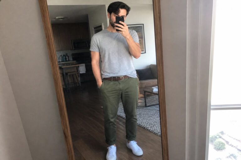 Man in gray t-shirt and olive pants taking mirror selfie with phone