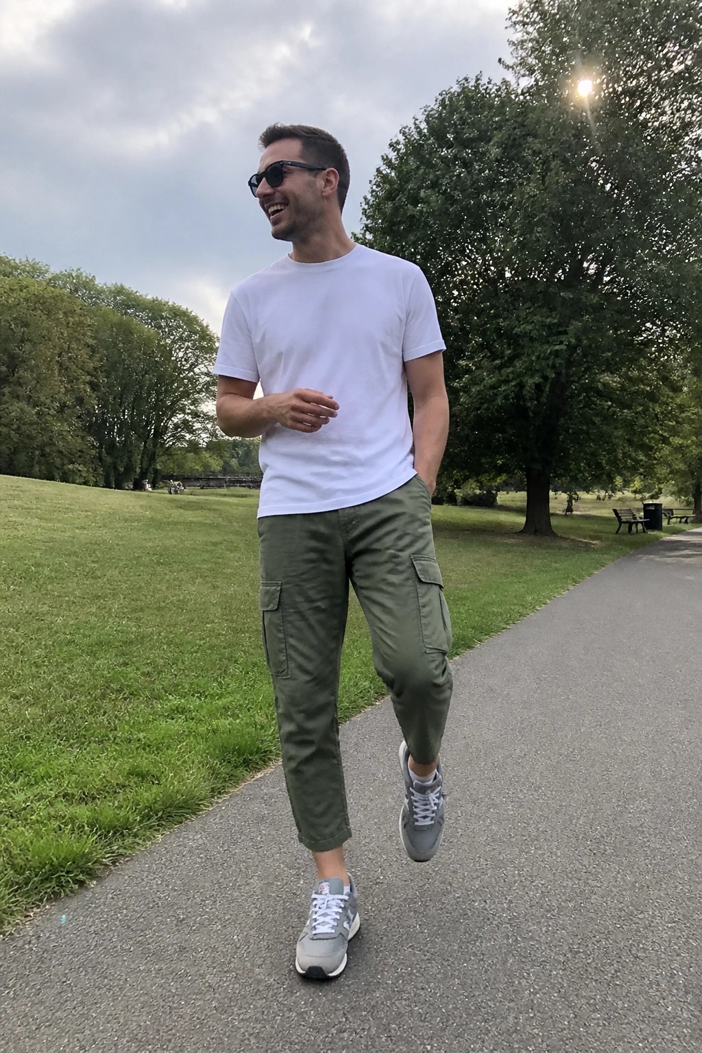 Man in white t-shirt and green cargo pants walking on park path