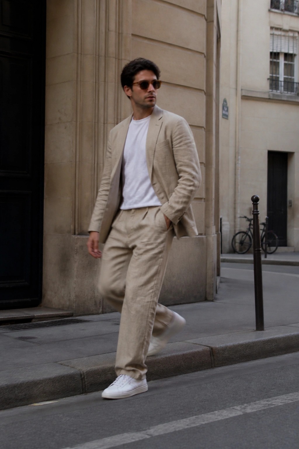 Man in beige linen suit, white t-shirt, and sneakers on city sidewalk