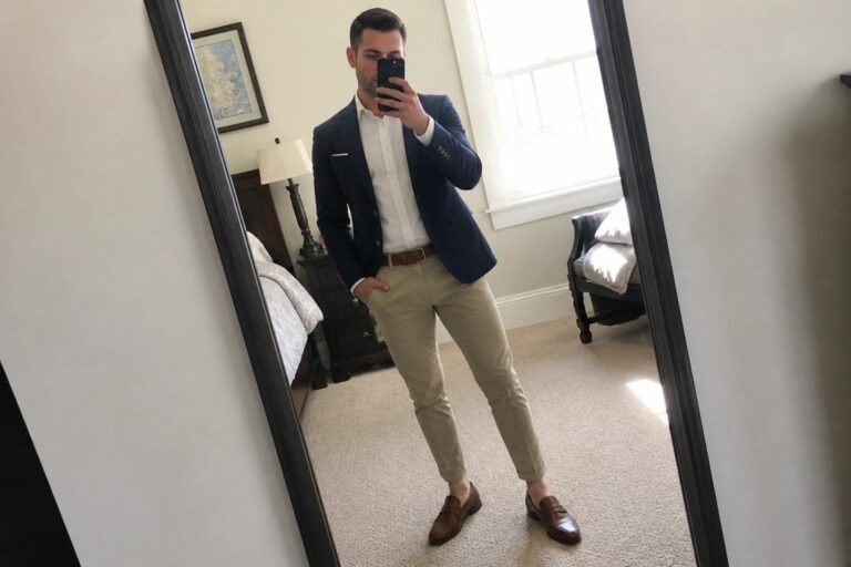 Man in navy blazer and khakis taking mirror selfie with phone