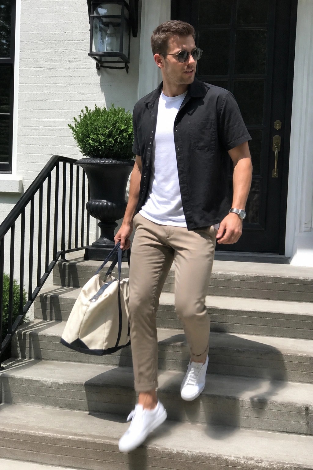 Man in black shirt and khaki pants carrying tote bag down stone steps