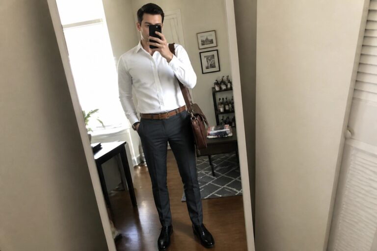 25 Professional Formal Pants Outfits for Men That Balance Comfort and Authority Man in white shirt and gray pants taking mirror selfie with leather bag