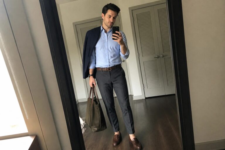 Man in light blue shirt and blazer taking mirror selfie with green tote bag