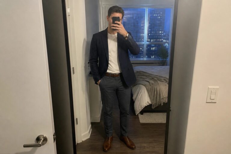 22 Stylish Men’s Smart Casual Date Night Outfits That Feel Effortlessly Polished Man in navy blazer, white tee, gray pants, and brown shoes taking mirror selfie in bedroom
