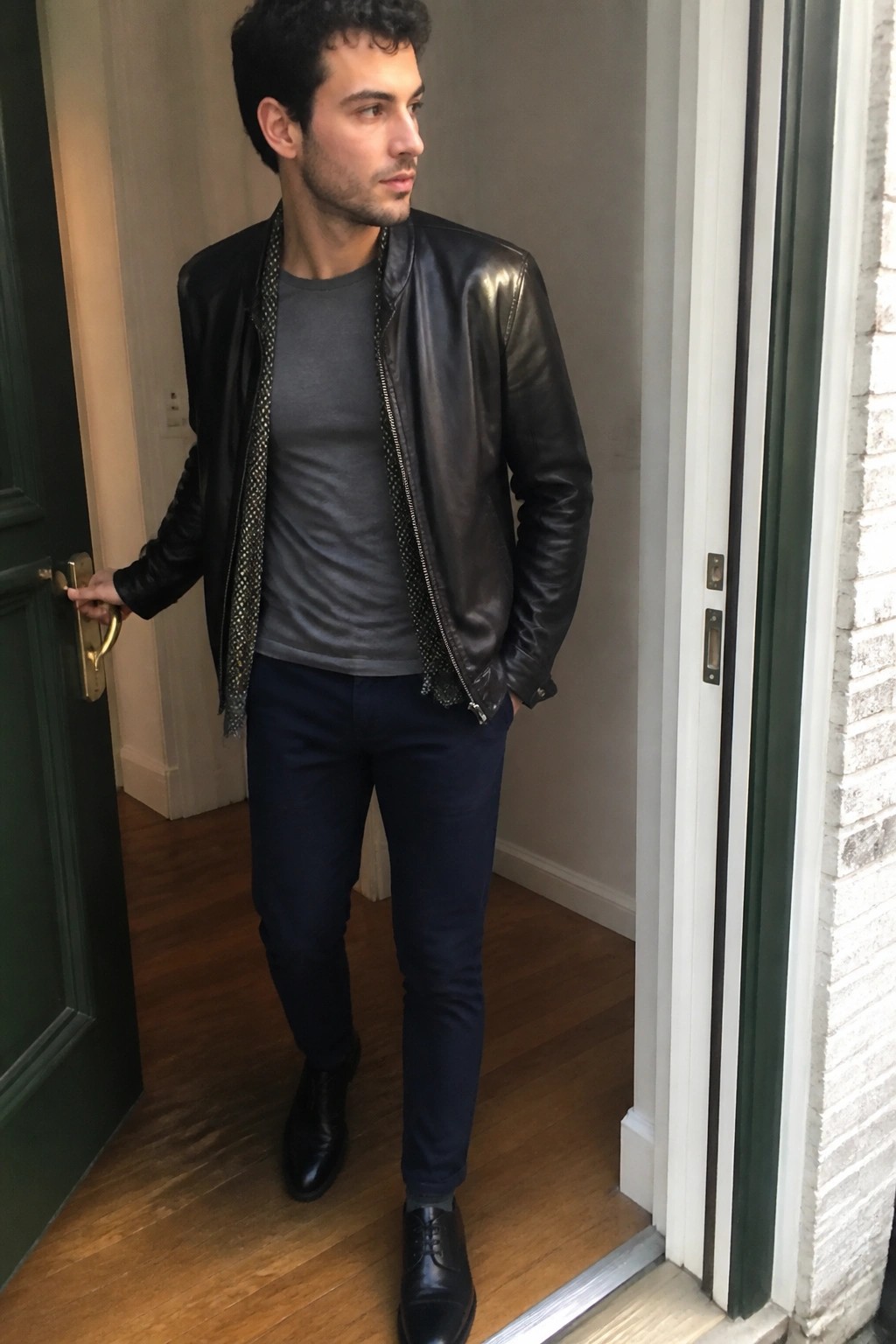 Man in open black leather jacket over gray shirt in doorway