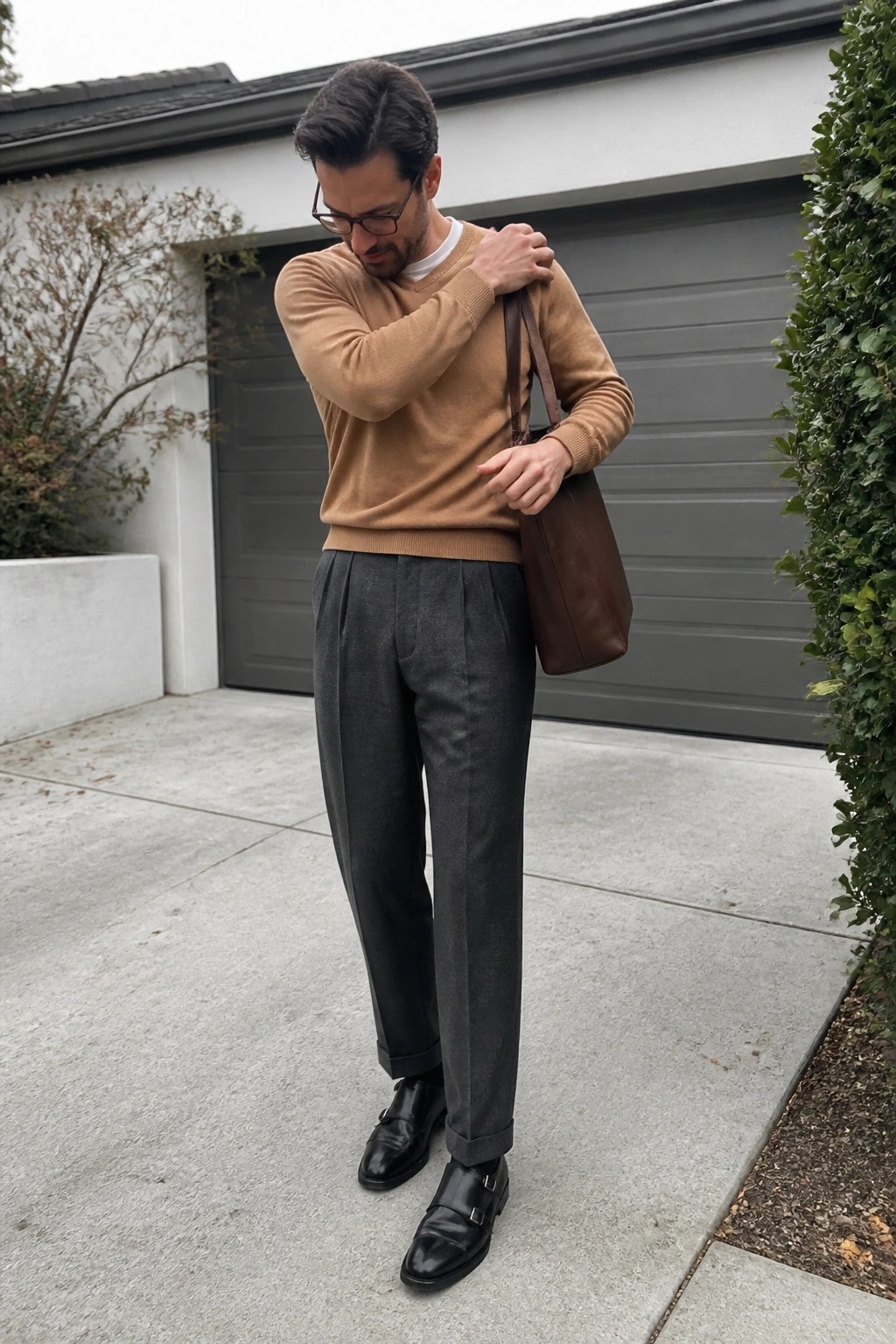 Man in tan sweater and gray trousers with brown leather tote bag outdoors