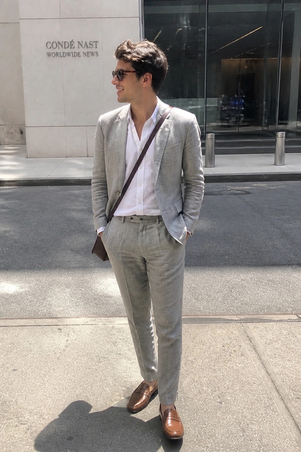 Man in light gray suit and white shirt on sunny city sidewalk