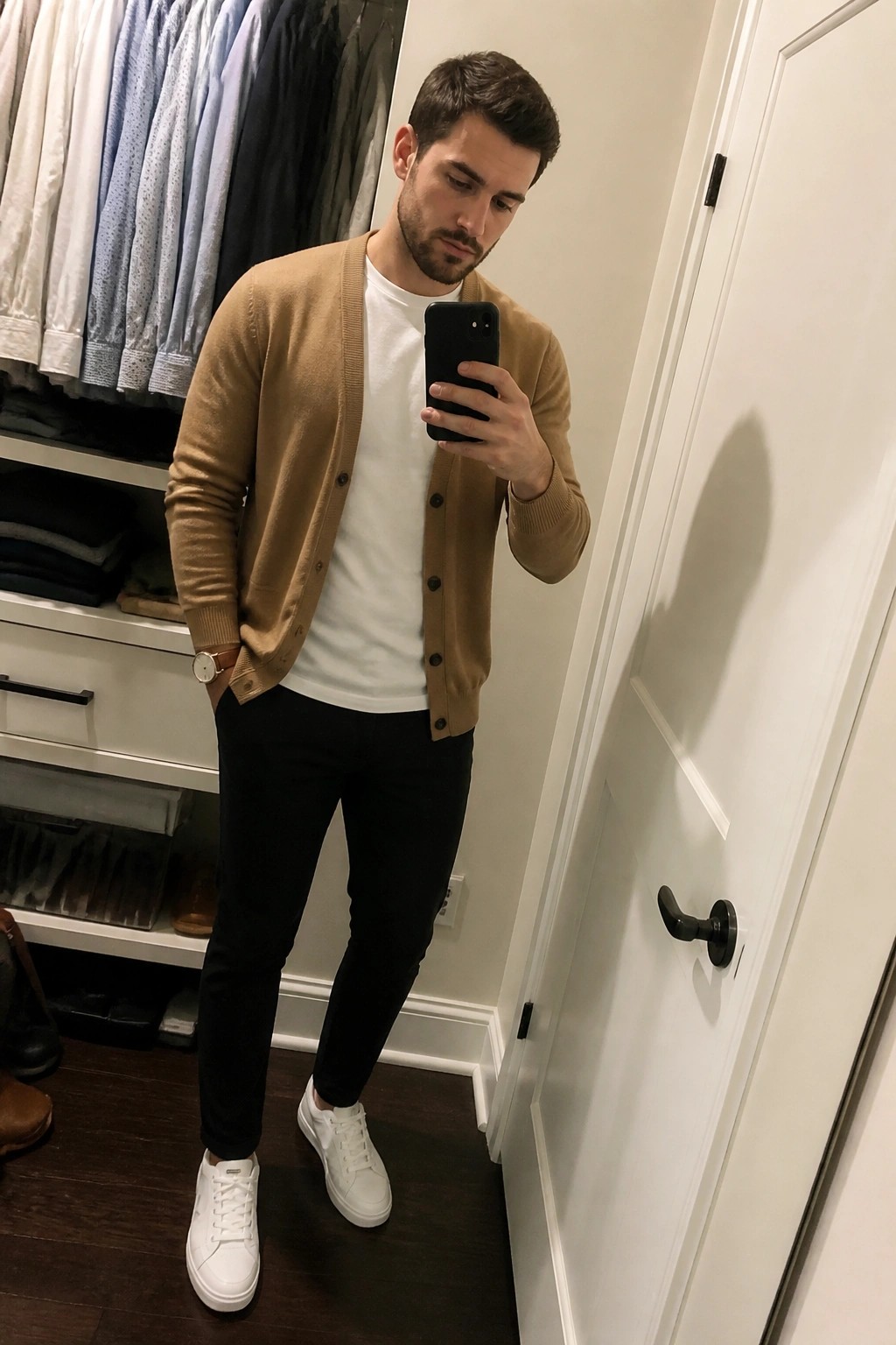 Man in tan cardigan taking mirror selfie in walk-in closet