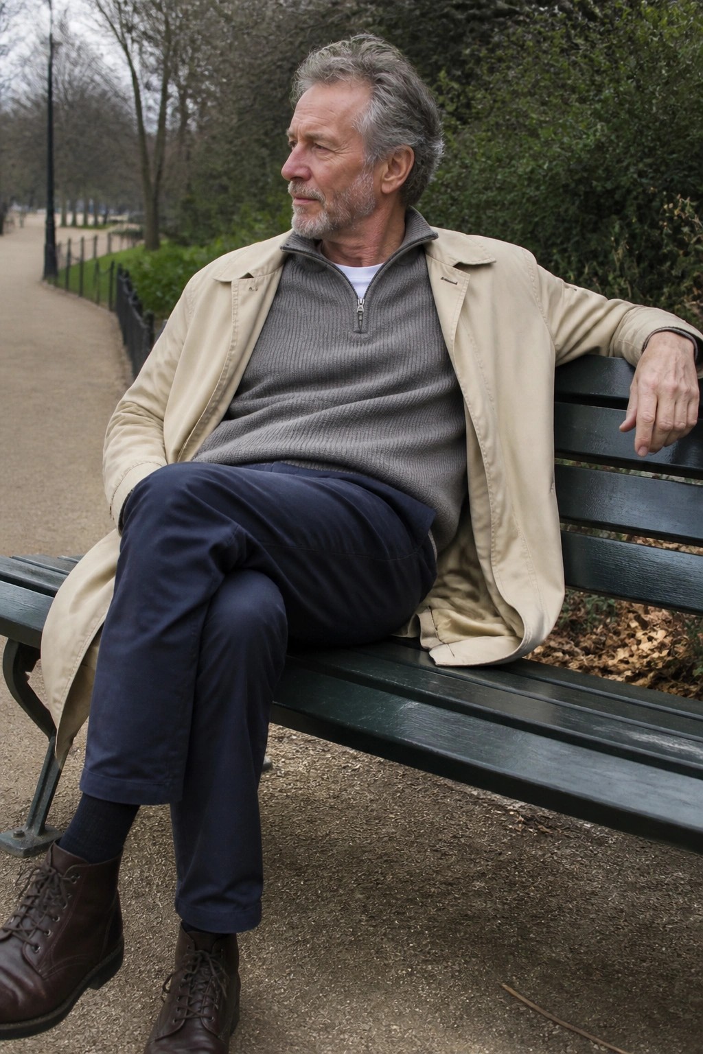 Gray-haired man in beige jacket sits on green park bench looking aside
