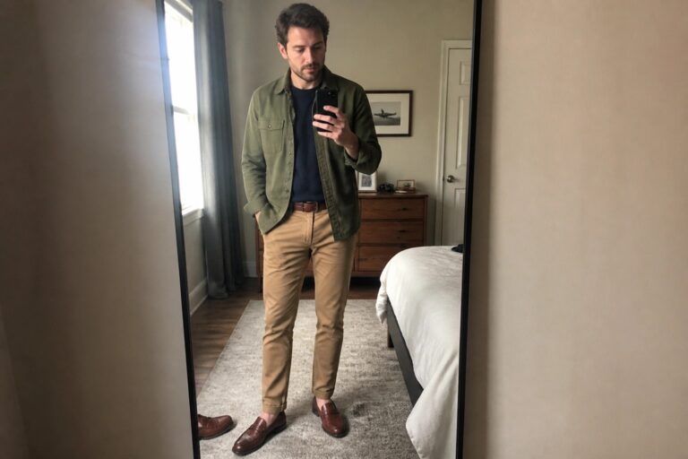 19 Old Money Fall Outfits for Men Using Olive, Navy, and Camel Layers Man in green jacket and tan pants takes mirror selfie in bedroom.