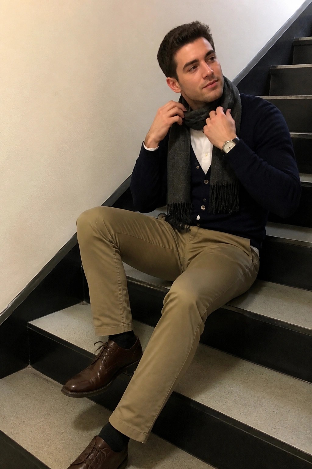 Stylish man in navy sweater, beige pants, and gray scarf on stairs