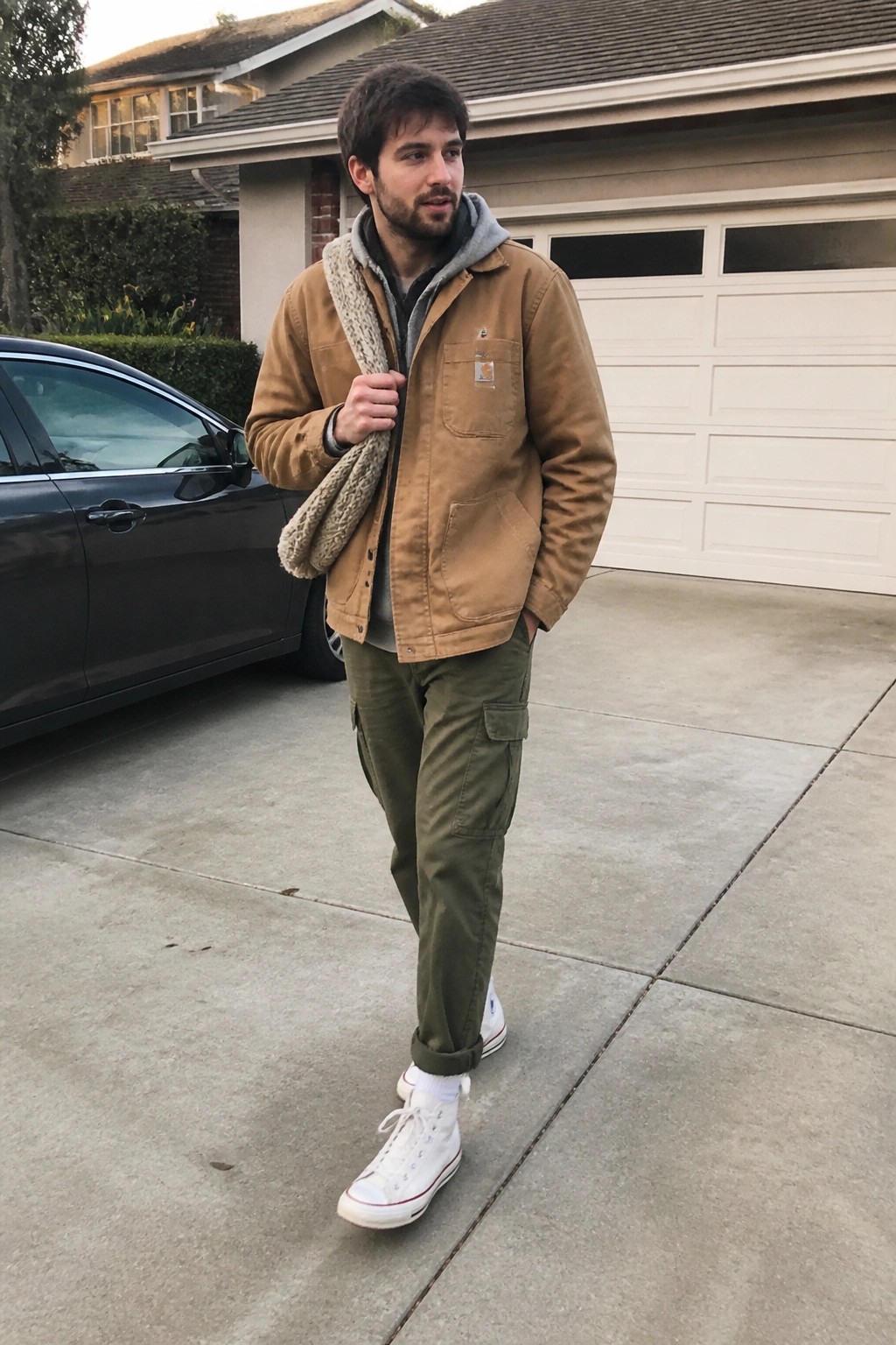 Man in brown Carhartt jacket and green cargo pants on suburban driveway