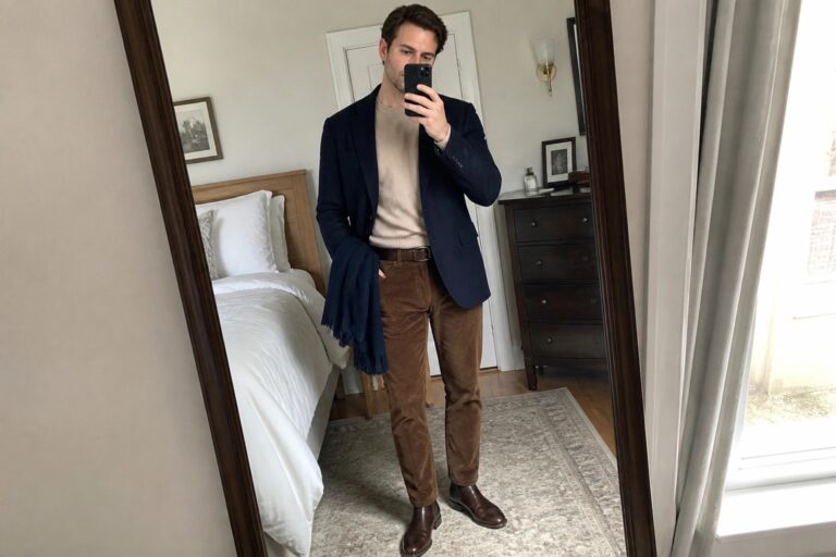 19 Stylish Brown and Navy Fall Outfits for Men Built Around Classic Menswear Staples Man in navy blazer, beige sweater, brown corduroy pants and blue scarf taking mirror selfie.