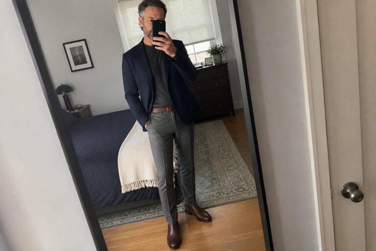 20 Sharp Fall Outfits for Men Over 40 With Tailored Fits and Classic Layers Man in navy blazer over turtleneck with gray pants taking mirror selfie in bedroom