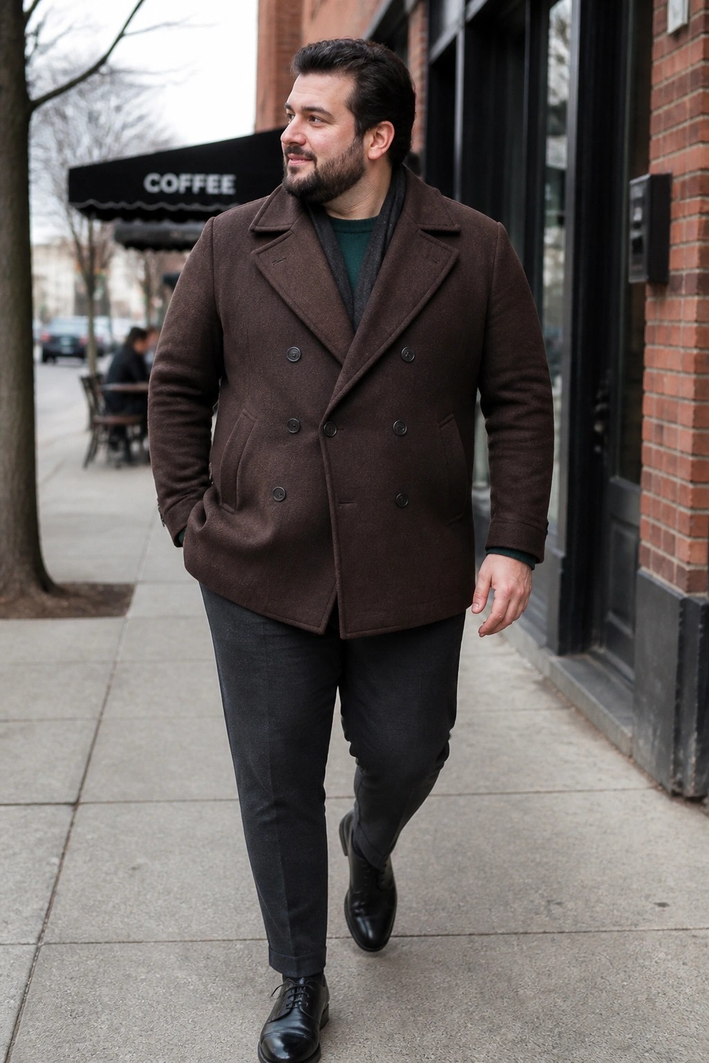 Man in brown double-breasted coat walking on city sidewalk by coffee shop