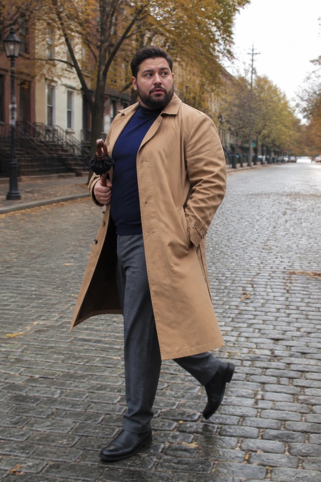 Bearded man in tan trench coat holds umbrella on fall cobblestone street
