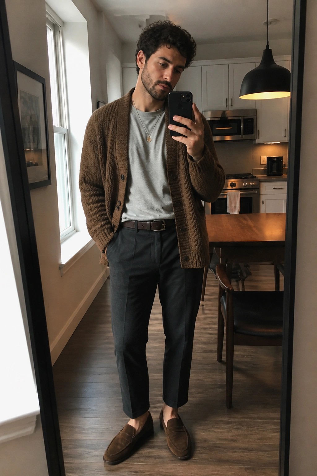 Man in brown cardigan and gray shirt taking mirror selfie in kitchen