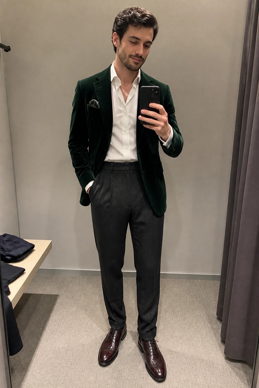 Man in green velvet blazer, white shirt, and gray trousers taking mirror selfie