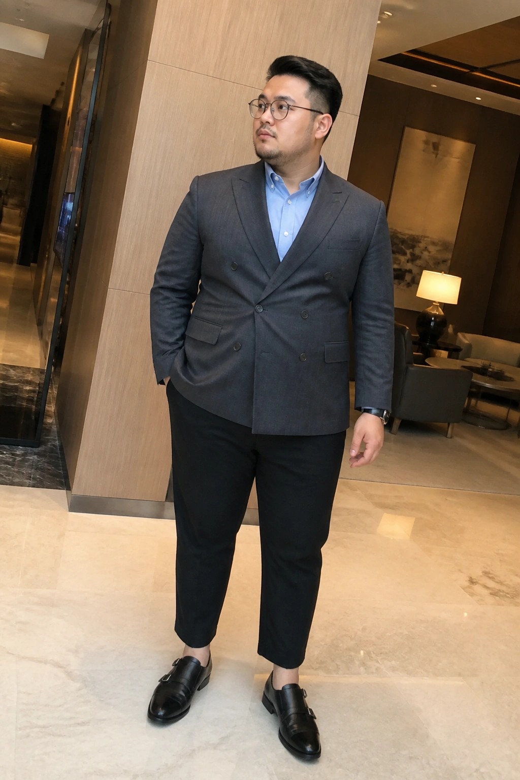 Man in gray double-breasted suit, blue shirt, black cropped trousers in lobby